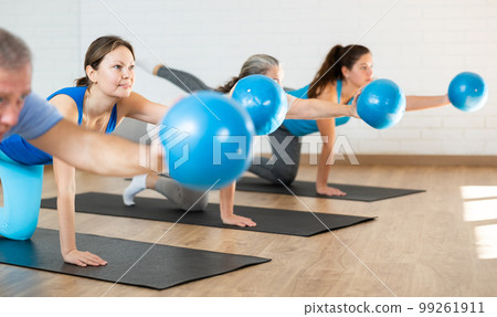Middle-aged woman practicing pilates with ball in gym area Middle-aged woman practicing pilates with ball in gym area 99261911