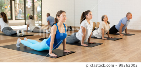 Middle-aged woman practicing pilates on mat in gym area Middle-aged woman practicing pilates on mat in gym area 99262002