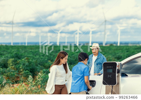 Concept of progressive happy family at wind farm with electric vehicle. Concept of progressive happy family at wind farm with electric vehicle. 99263466