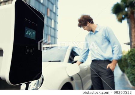 Progressive concept of focus EV car at charging station with blur man background 99263532