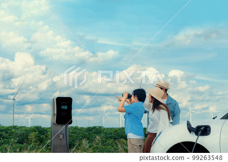 Concept of progressive happy family at wind farm with electric vehicle. 99263548