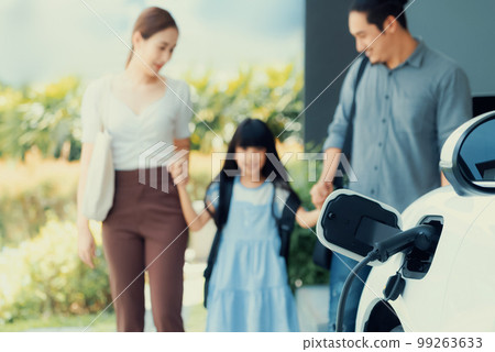 Focus home charging station for EV car, blur progressive family in background. 99263633