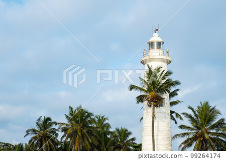 Galle Fort lighthouse UNESCO world heritage site surrounded palm trees against blue sky. 99264174