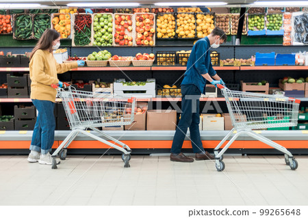 man and a woman with shopping carts in a supermarket during the quarantine period. 99265648