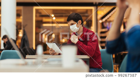 cafe patrons in protective masks working on their laptops 99267387