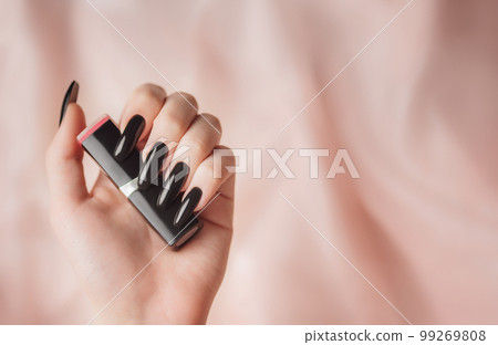 The hand of a young girl with a bright black manicure on her nails. The hand of a young girl with a bright black manicure on her nails. 99269808