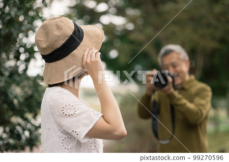 Senior man taking a picture of a woman 99270596