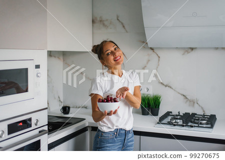 Happy nutritionist woman holds a fresh cherry berry in a plate in her hand. The concept of healthy eating and diet Happy nutritionist woman holds a fresh cherry berry in a plate in her hand. The concept of healthy eating and diet 99270675