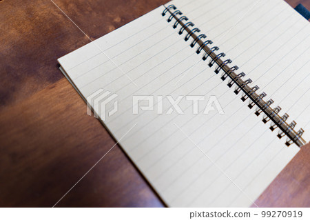 Close up of open notebook on wooden table Close up of open notebook on wooden table 99270919