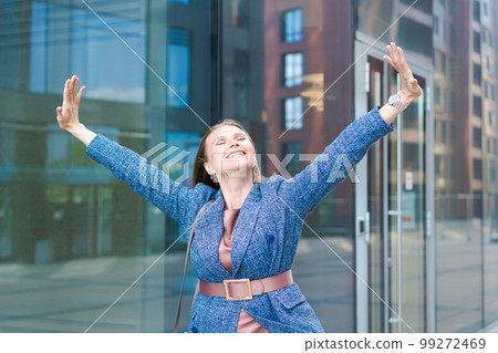 Happy business woman showing thumbs up while standing outdoors against office 99272469