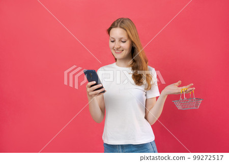 Happy beautiful girl holding mini shopping cart Using smartphone select 99272517