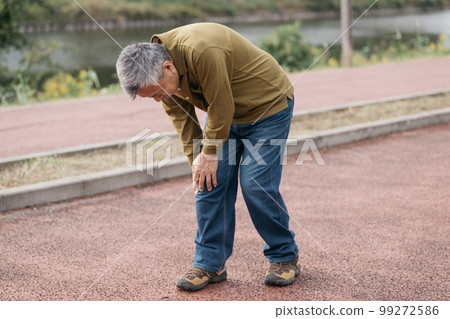 Senior man with knee pain walking along the river 99272586