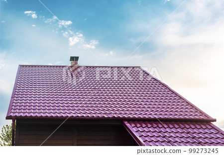 Roof of a house with a red tile roof under a clear blue sky in summer. 99273245