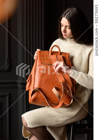 photo of a woman with a orange leather backpack with antique and retro look. indoors photo 99275693