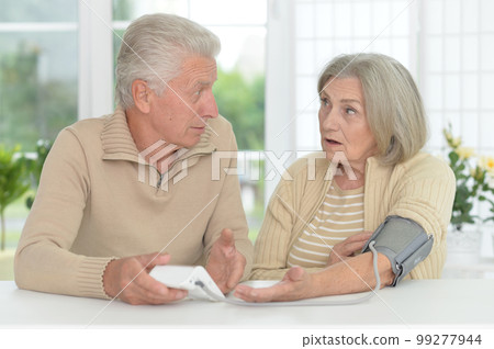 old couple measuring blood pressure together old couple measuring blood pressure together 99277944