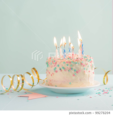 Festive cake with candles on blue background, sequins serpentine, confetti. concept of holiday Festive cake with candles on blue background, sequins serpentine, confetti. concept of holiday 99278204