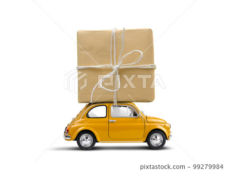 Retro yellow toy car delivering gift box atop on a white background 99279984