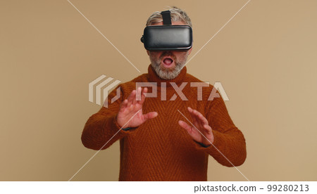 Senior man using virtual reality headset helmet to play simulation game app, watching video content 99280213