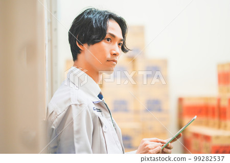 Young businessman wearing work clothes and managing inventory in a warehouse 99282537