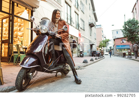 Portrait of attractive young cheerful woman riding moped scooter Portrait of attractive young cheerful woman riding moped scooter 99282705