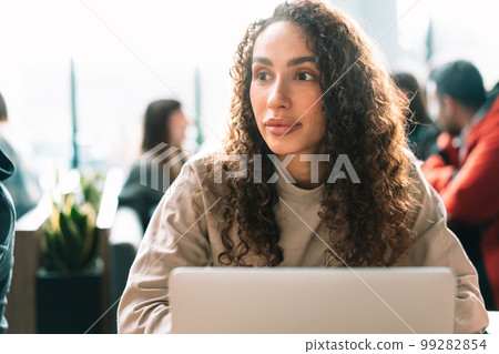 Young beautiful woman sitting at the table and using laptop in cafe. 99282854