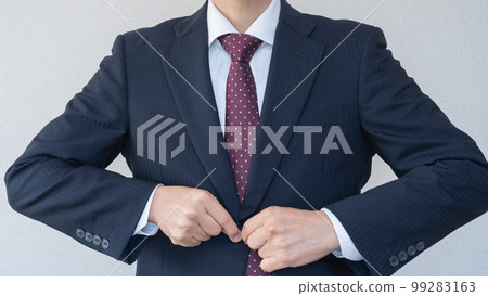 A businessman in a suit buttoning up his jacket 99283163