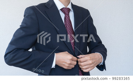 A businessman in a suit buttoning up his jacket A businessman in a suit buttoning up his jacket 99283165