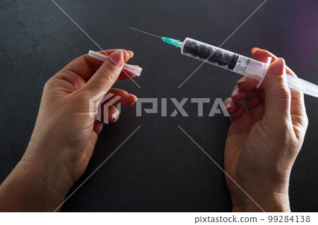 Grains of coffee and an injection syringe in female hands. Caffeine addiction concept. Grains of coffee and an injection syringe in female hands. Caffeine addiction concept. 99284138