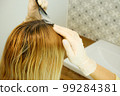 Hair coloring at home. The girl herself dyes the regrown hair roots. 99284381