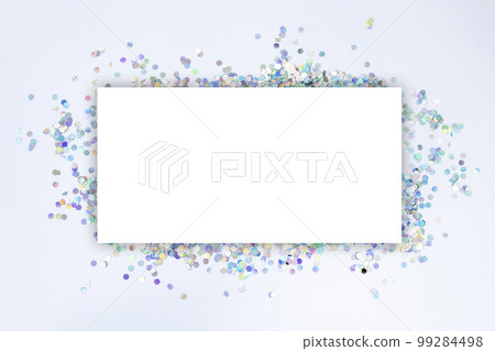 White blank mock-up sheet with a background of silver holographic confetti scattered on the surface. White blank mock-up sheet with a background of silver holographic confetti scattered on the surface. 99284498