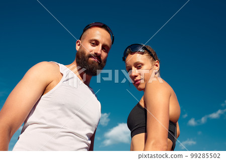 Handsome young athletes looking at the camera and smiling while training at the city stadium, diversity men and women are jogging. 99285502