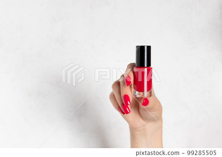 close-up of woman's hand with red nail design holding nail polish bottle. close-up of woman's hand with red nail design holding nail polish bottle. 99285505