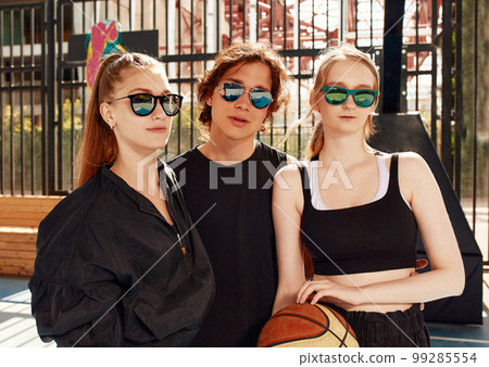 A friendly company of guys and girls are having fun on the basketball court, they are going to play basketball. 99285554