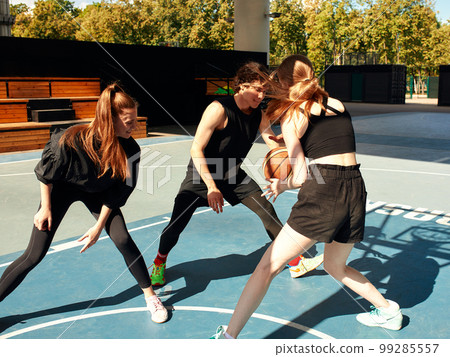 A friendly company of guys and girls are having fun on the basketball court, they are going to play basketball. 99285557