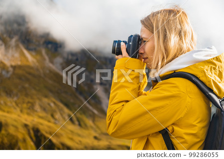 Close up pretty girl taking photos of mountains in Italian Alps on a retro camera. Close up pretty girl taking photos of mountains in Italian Alps on a retro camera. 99286055