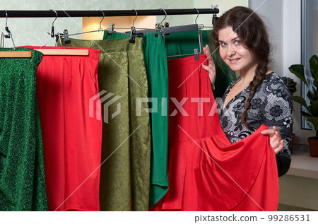 Portrait of a woman on the background of clothes in the dressing room Portrait of a woman on the background of clothes in the dressing room 99286531