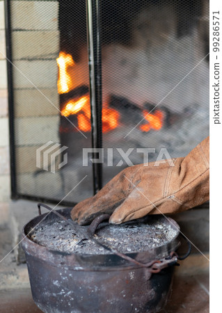 Cooking in an old dutch oven on the fireplace in a mountain hut Cooking in an old dutch oven on the fireplace in a mountain hut 99286571