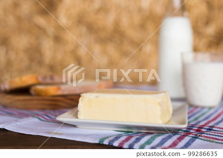 butter, dairy products and bread on the table against the background of hay 99286635
