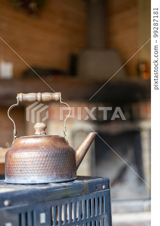 An old metal kettle on top of the stove in a mountain hut 99287181