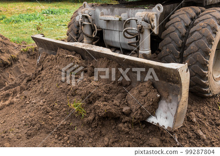 Excavator or bulldozer bucket flattens the ground or road in the industrial zone or construction site 99287804