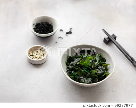 bowl with wakame seaweed with chopsticks and sesame seeds  99287977