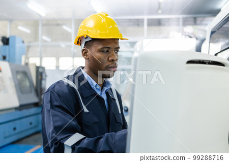 Man African American engineer using computer controlling cnc machine at workshop. Man African American engineer using computer controlling cnc machine at workshop. 99288716
