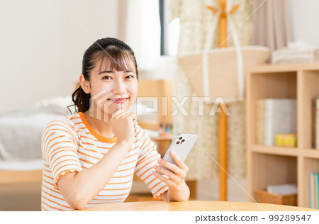 A young woman using a smartphone in the living room 99289547
