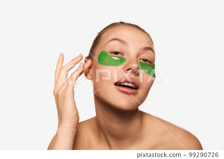 Closeup young charming girl with bare shoulders using with eye patches for skin refresh. Concept of beauty, natural make-up, skin care, healthy look 99290726