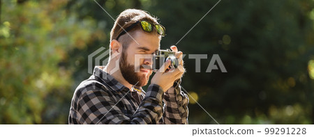 Banner Portrait man photographer taking picture with vintage camera on city green park copy space and place for text - leisure activity and hobby concept 99291228