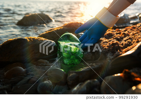 Conservation of ecology. A volunteer picks up plastic bottles by the sea or river. Coastal cleaning and garbage collection for recycling. World environment day concept 99291930