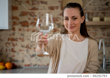 Healthy lifestyle is my choice. An active smiling woman looks into the camera, holding a glass of pure still water. A pretty woman promotes drinking water as an easy way to take care of health 99292765