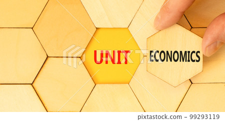 Unit economics symbol. Concept words Unit economics on wooden puzzles. Beautiful yellow table yellow background. Businessman hand. Business and unit economics concept. Copy space. Unit economics symbol. Concept words Unit economics on wooden puzzles. Beautiful yellow table yellow background. Businessman hand. Business and unit economics concept. Copy space. 99293119