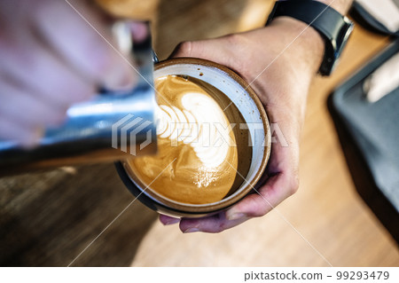 Barista makes coffee in a coffeeshop. Cup of cappuccino or latte in the making. Selected focus 99293479