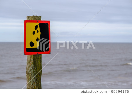 A warning sign about a possible landslide near the seashore. Reflects the idea of the concept of caution and warning signs. 99294176